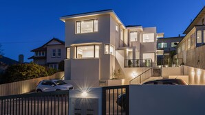 A modern two-story house with a well-lit entrance and a gated driveway. - 110 Hampden Apartments (Battery Point)