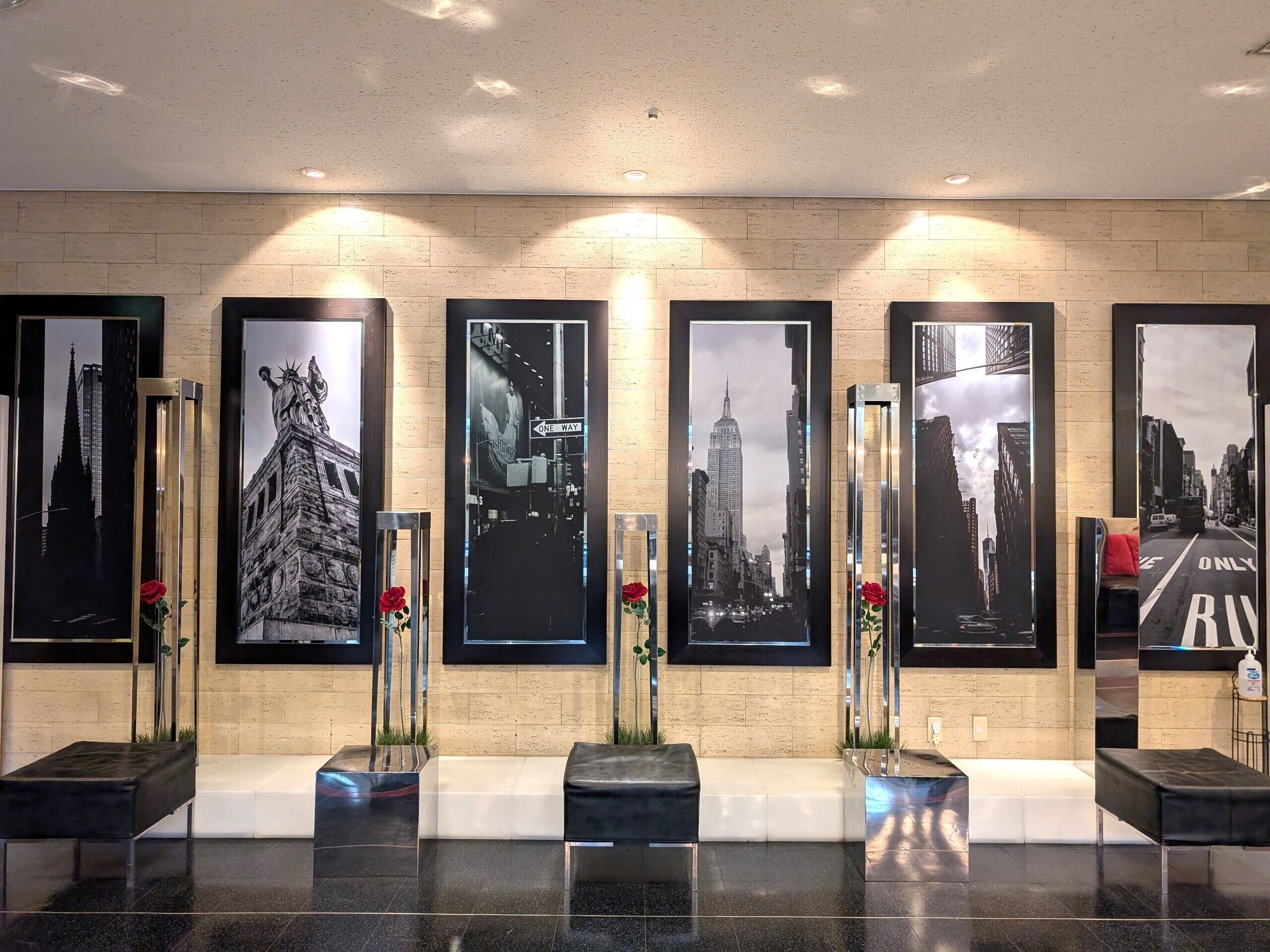 A reception area with a tiled wall, framed cityscape photographs, and a bench.