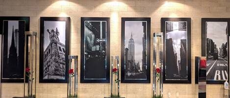 A reception area with a tiled wall, framed cityscape photographs, and a bench.