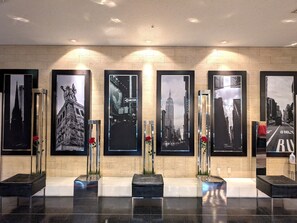 Een receptie met een betegelde muur, stadsfotografie in lijsten, en een bank.