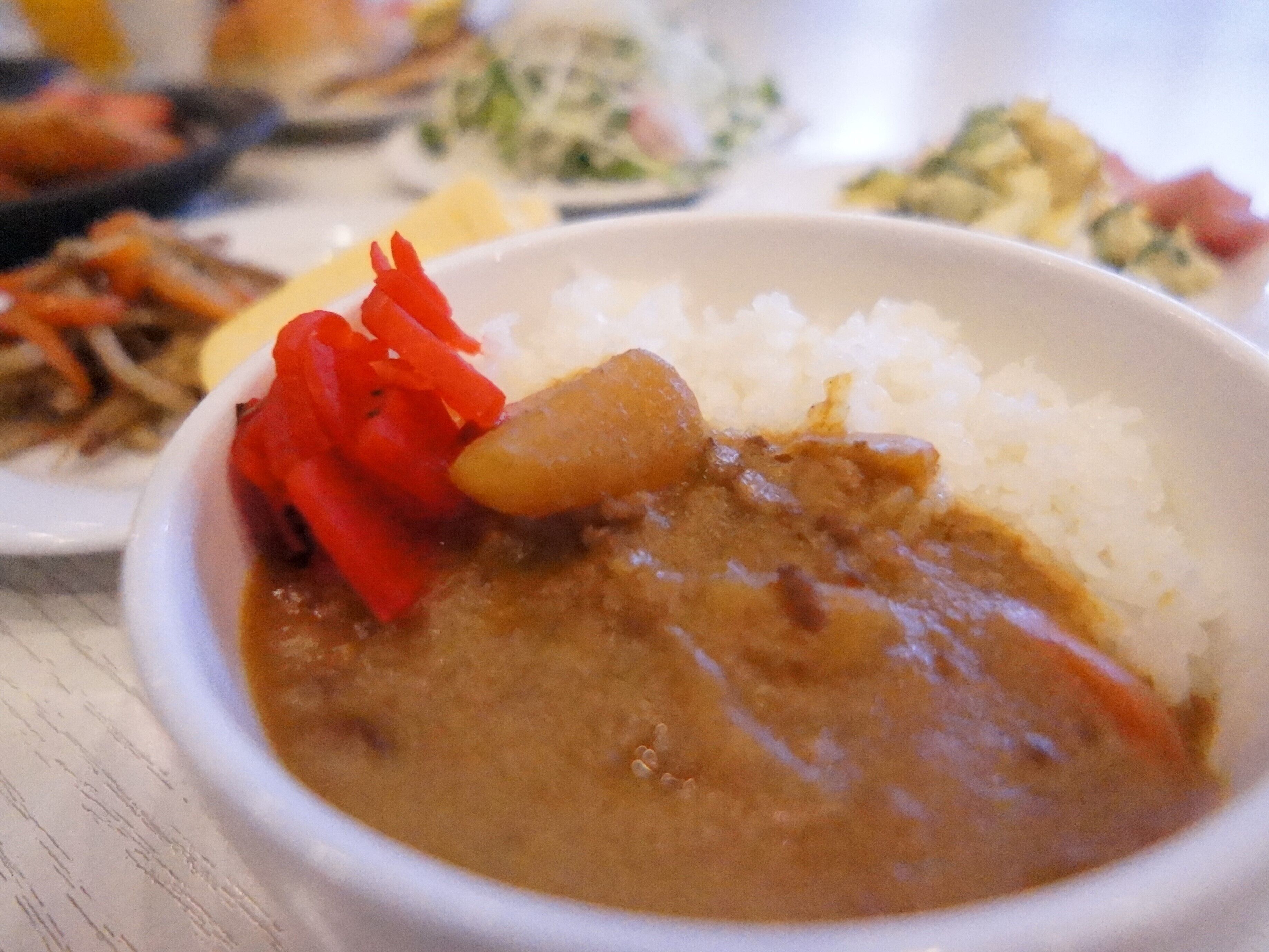 A bowl of curry with rice and red bell peppers.