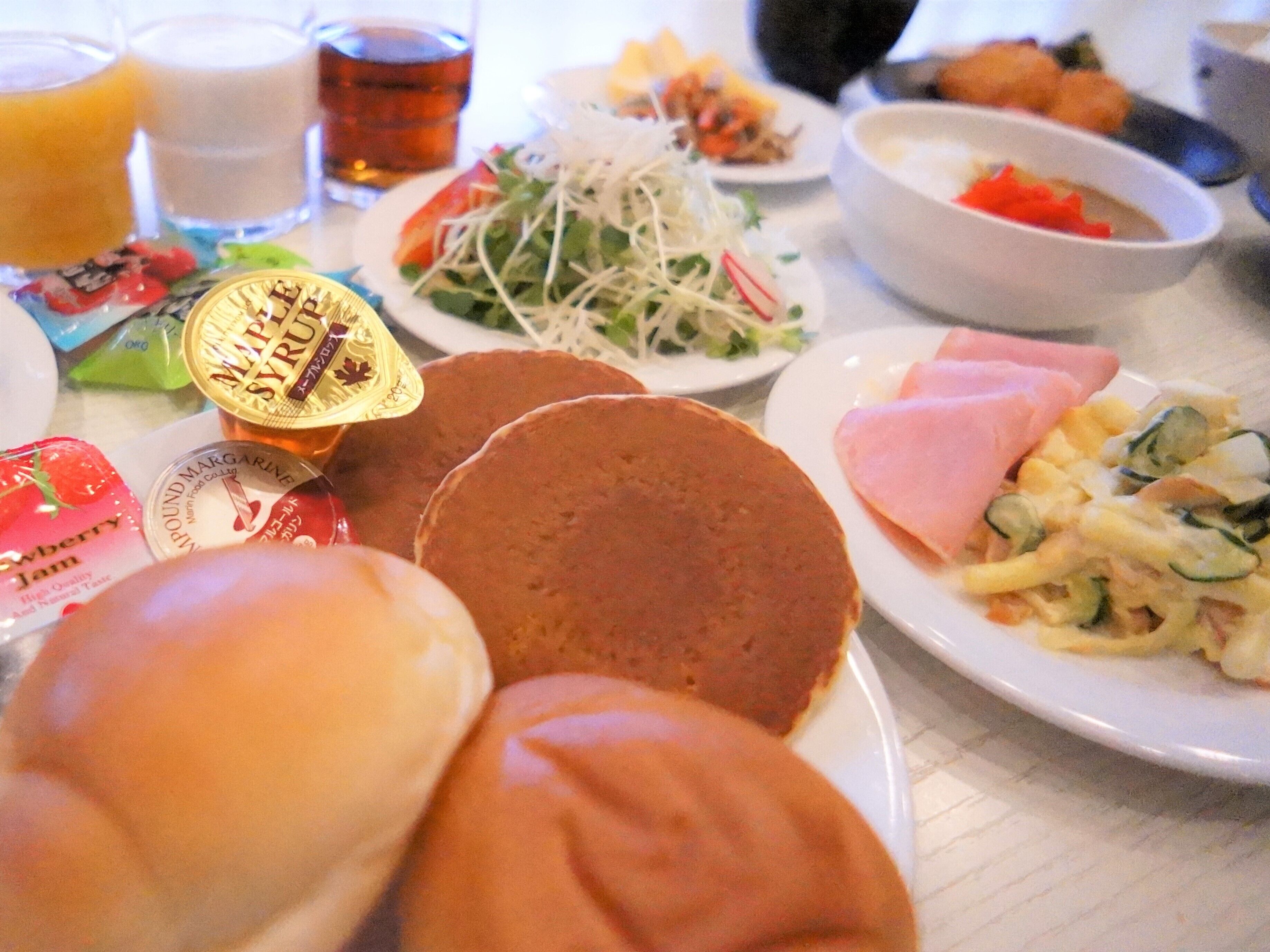 A table with various food items including pancakes, a salad, and a bowl of soup.