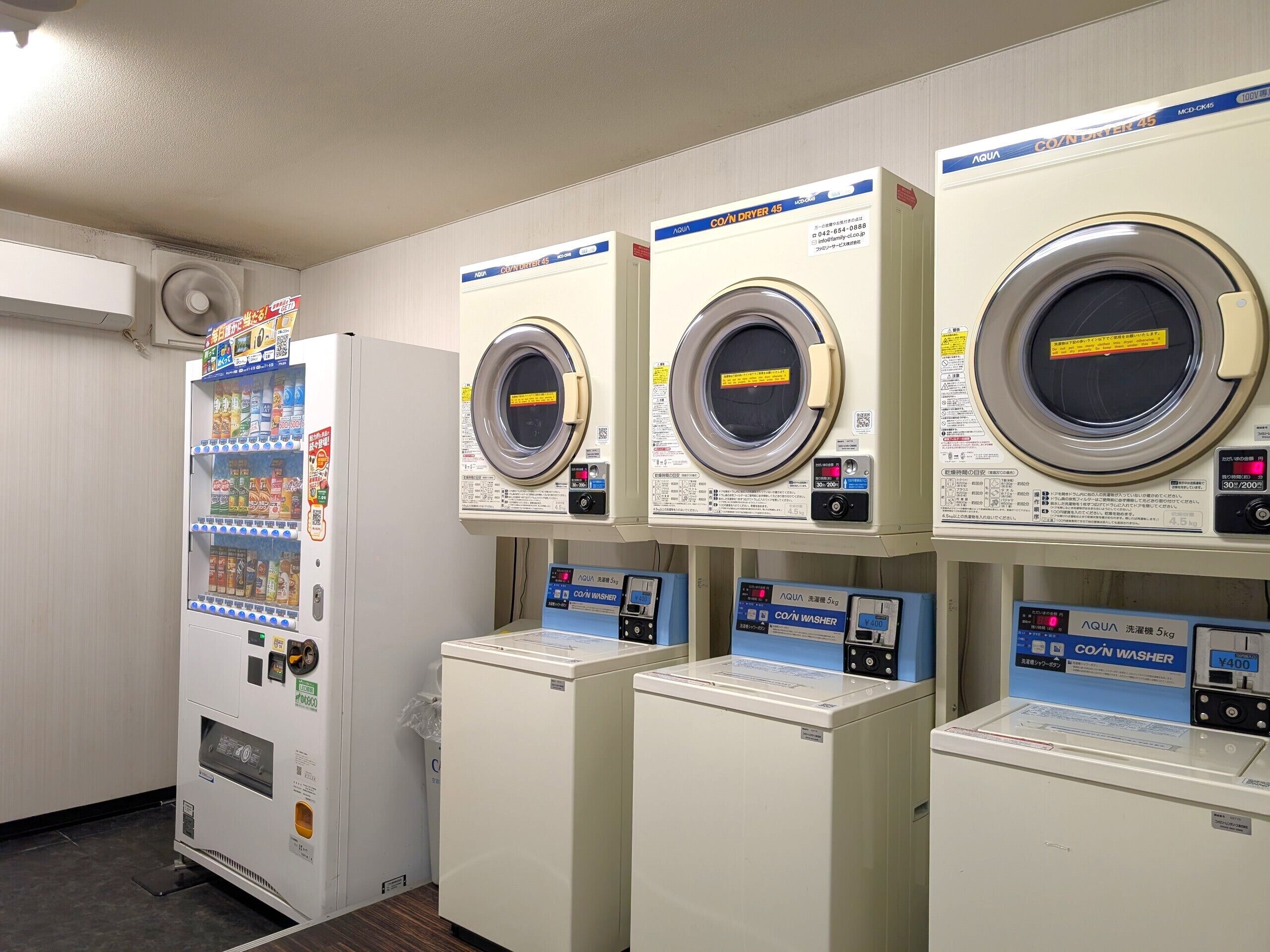 A laundry facility with multiple washing machines and a vending machine.