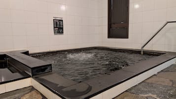 A hot tub with a tiled wall and a sign with Japanese text.