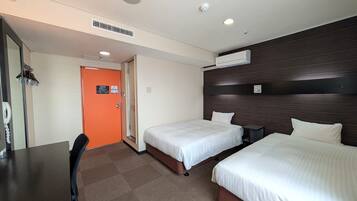 Ein Hotelzimmer mit zwei Betten, einem Schreibtisch und einer Badezimmertür.