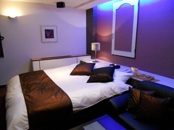 A hotel room with a bed, a bedside lamp, a framed picture on the wall, and a window with a view.