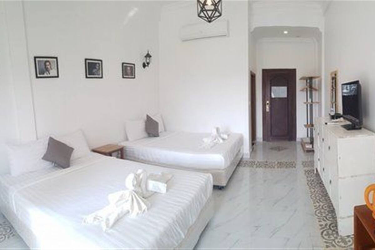 Habitación de hotel con dos camas, televisión, minibar y una puerta que da a otra habitación.