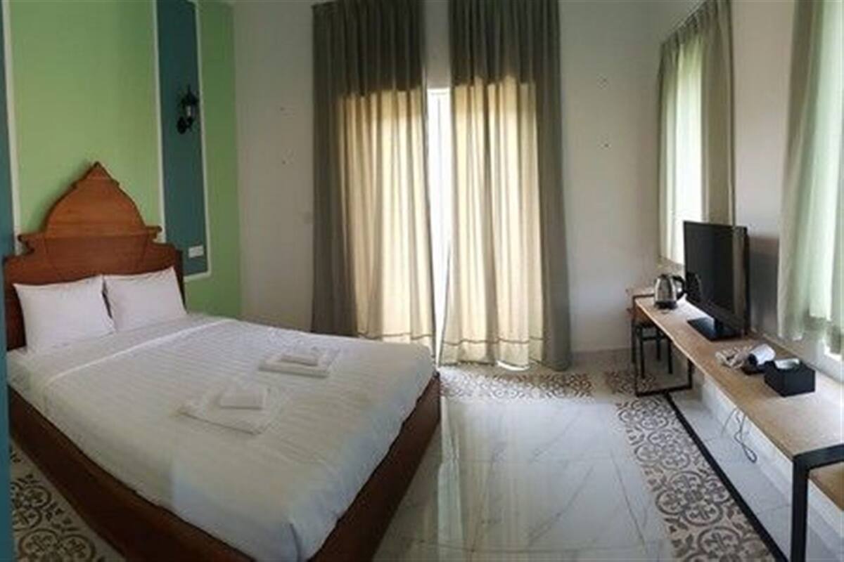 Habitación de hotel con cama, escritorio y televisión, además de cortinas.