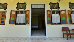 A room with a doorway leading to another space, a chair, and a patterned floor. - Baba La Casa Hotel (Chalong)