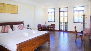 A hotel room with a large bed, two chairs, a small table, and a decorative plant. - Baba La Casa Hotel (Chalong)