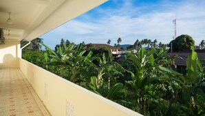 A balcony with a view of lush greenery and a distant building. - Baba La Casa Hotel (Chalong)