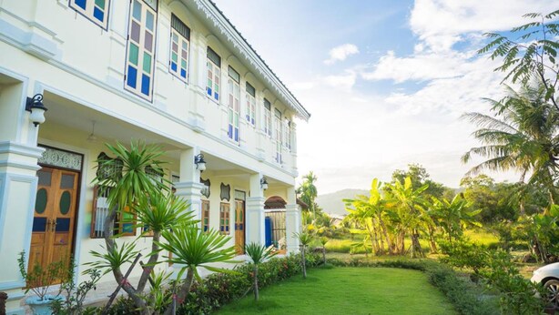 A colonial-style building with a white facade, multiple windows, and a covered porch. - Baba La Casa Hotel (Chalong)