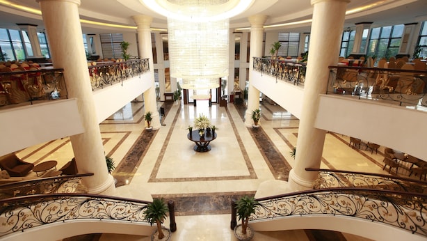 Un vaste hall d’entrée avec de hauts plafonds, de grands lustres et une composition florale centrale.