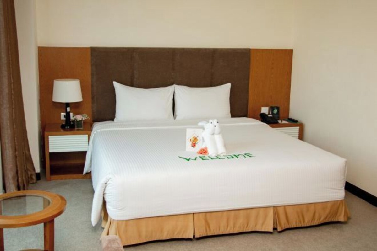 Une chambre d’hôtel avec un lit, une table de chevet, une lampe et une petite table.
