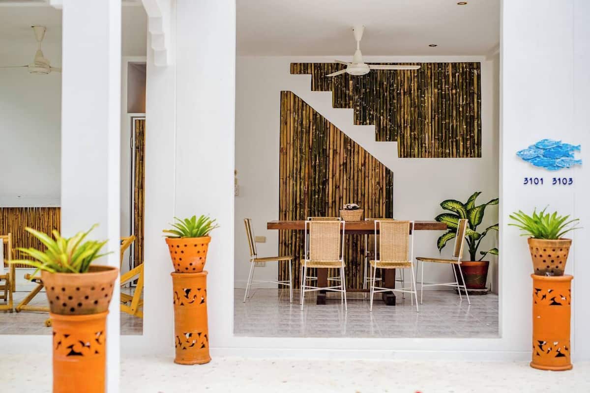 Um interior moderno com escada, área de jantar e plantas em vasos.