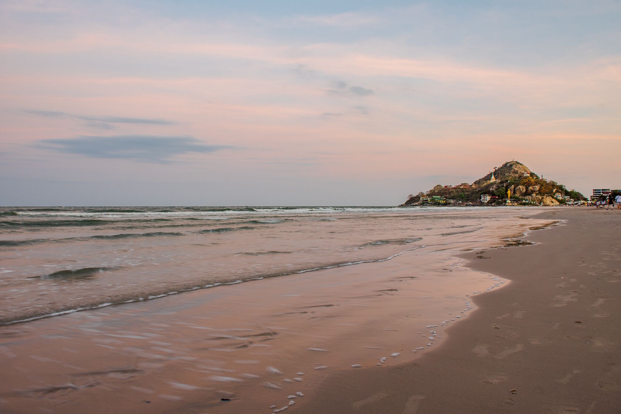 A beach with a rocky hill in the background.