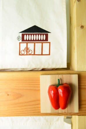 A white tote bag with a building and bicycle logo, placed on a wooden surface with two red peppers. - Kyoyado Okara - Hostel (Kyoto)