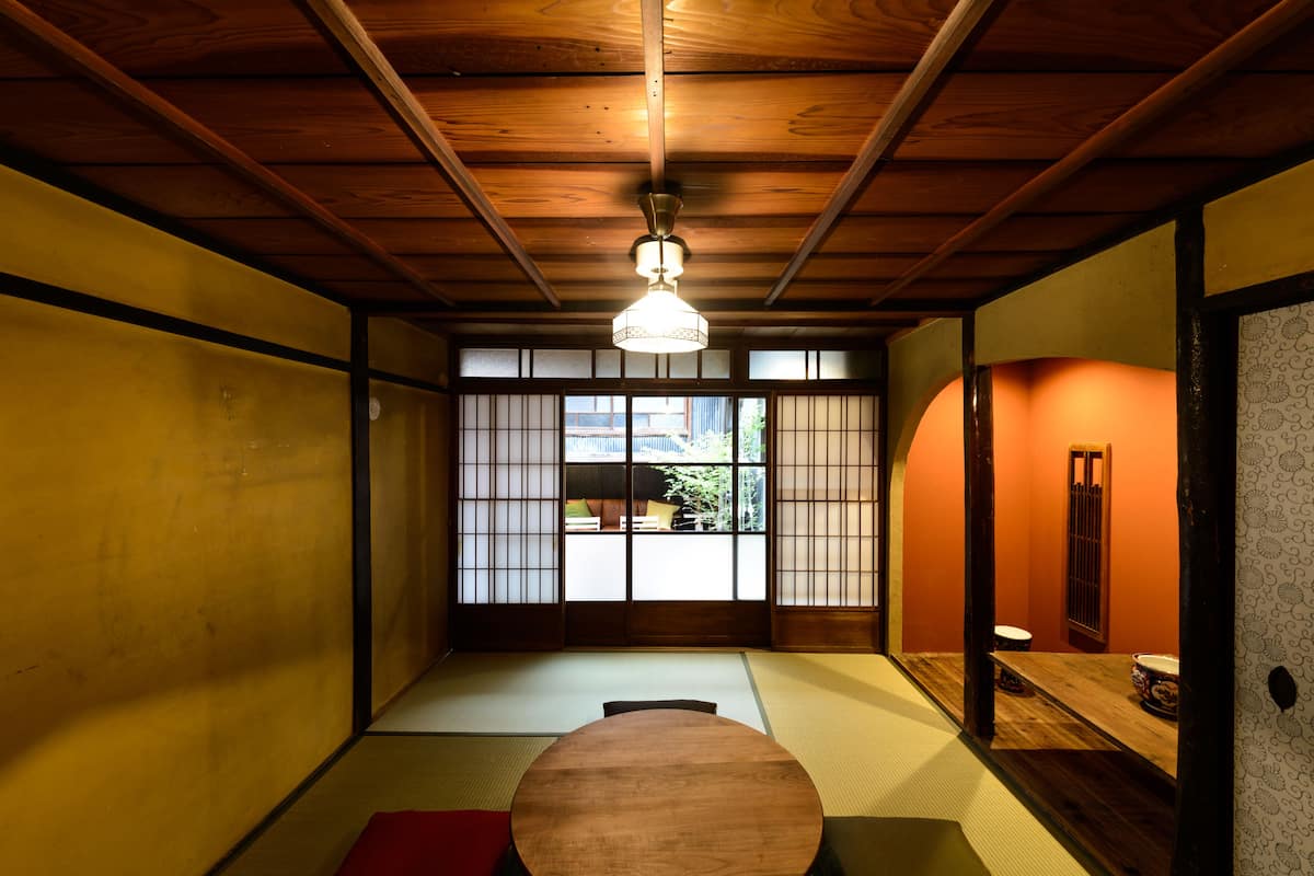 Una habitación tradicional japonesa con suelo de tatami, techo de madera y puertas correderas.