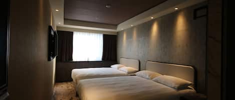 A hotel room with two beds, a flat-screen TV mounted on the wall, and a large window with curtains.