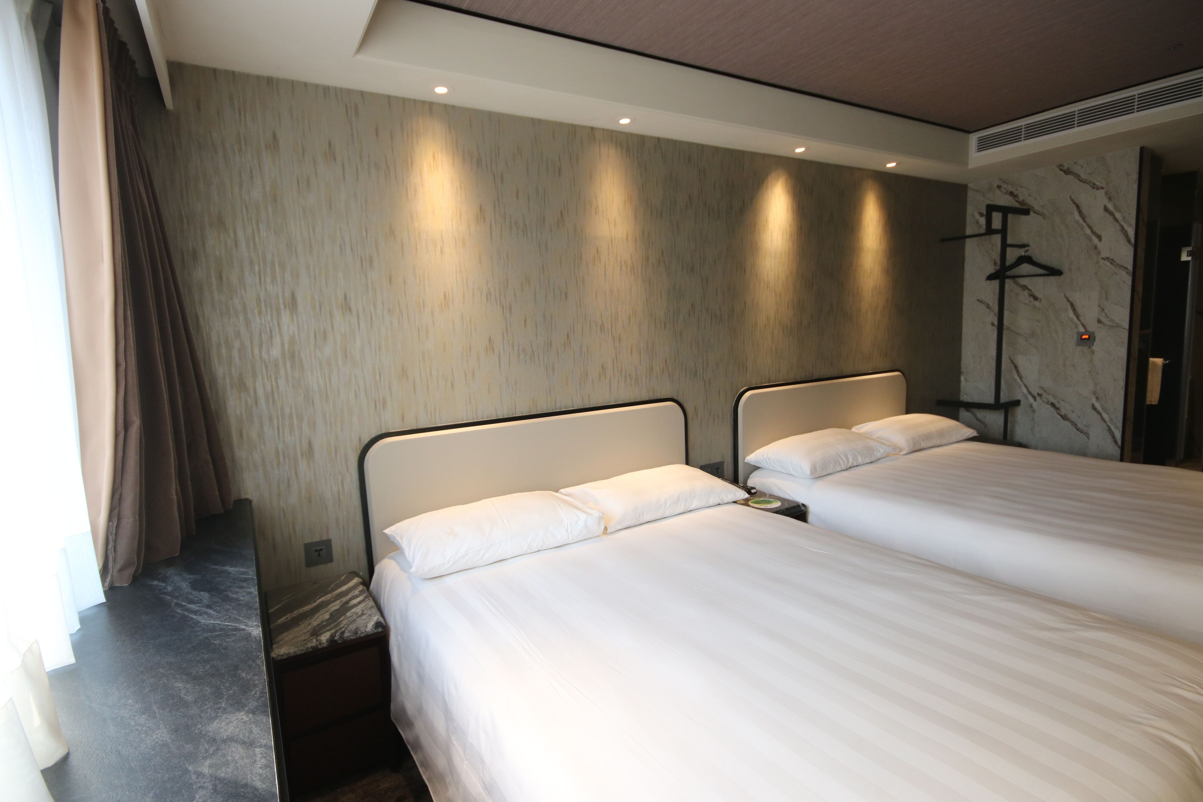 Ein Hotelzimmer mit zwei Betten, einer Marmorwand und einem modernen Design.