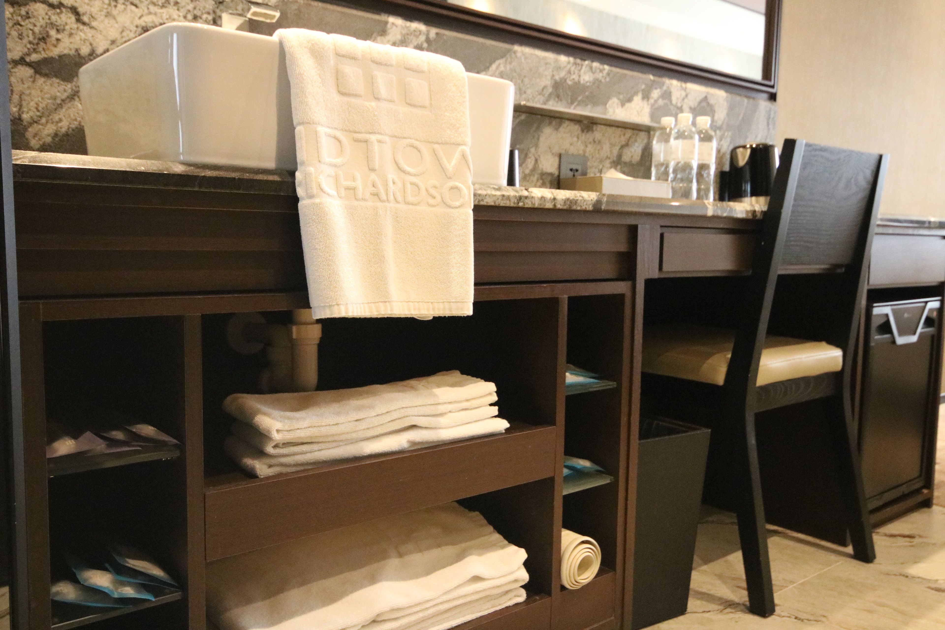 A bathroom with a marble countertop, a towel rack with a towel, and a chair.