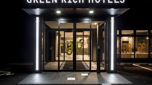 L'esterno dell'hotel Green Rich, con insegna illuminata e ingresso in vetro.