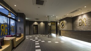 Una hall d'albergo con banco accettazione, area salotto e una grande finestra.