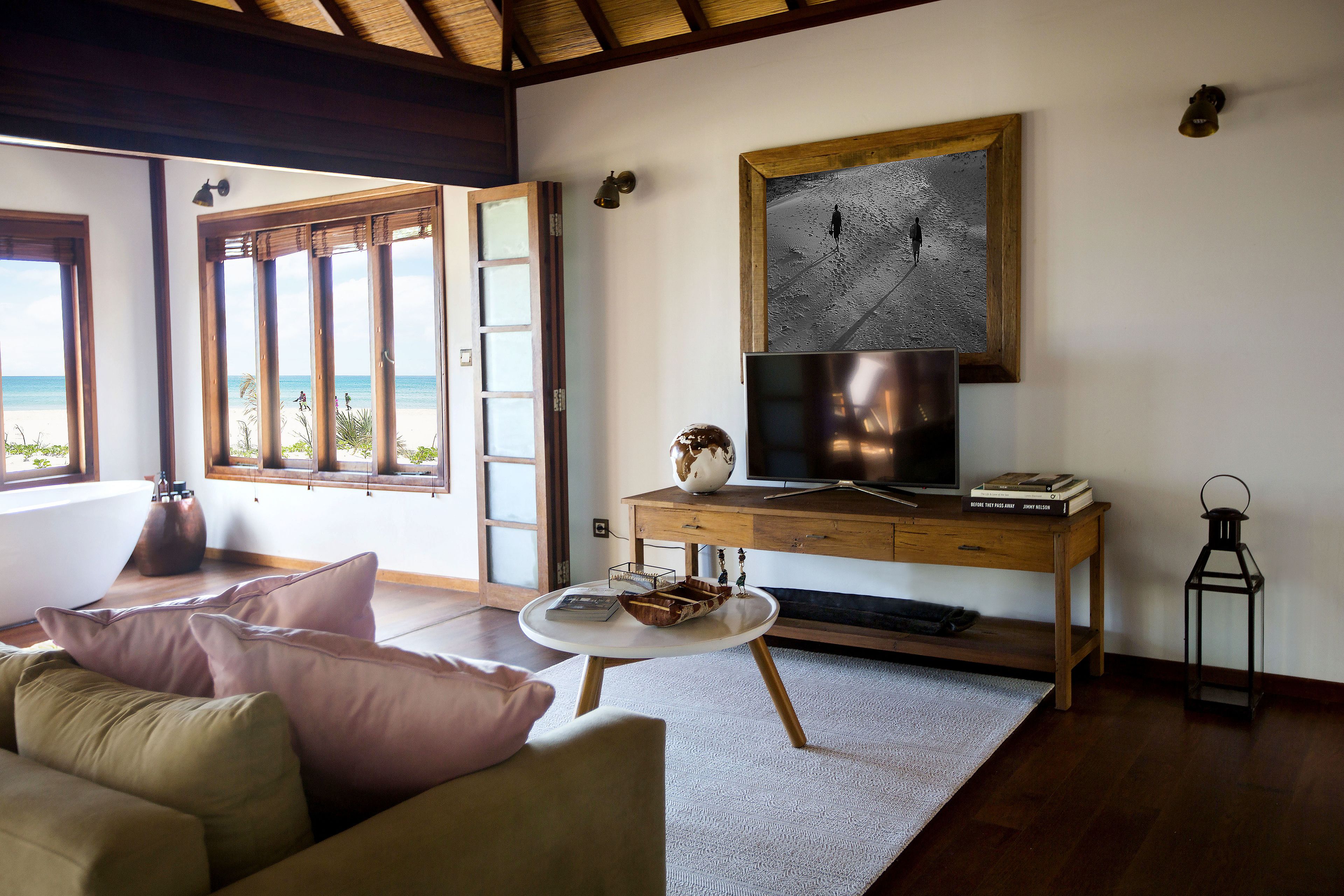 Una sala de estar con sofá, mesa de centro, escritorio de madera, televisor y un cuadro.