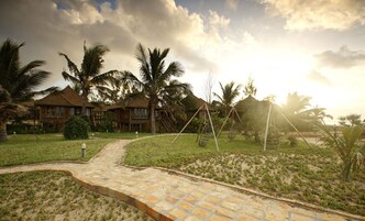 Un resort con villas de madera, un sendero pavimentado y palmeras.