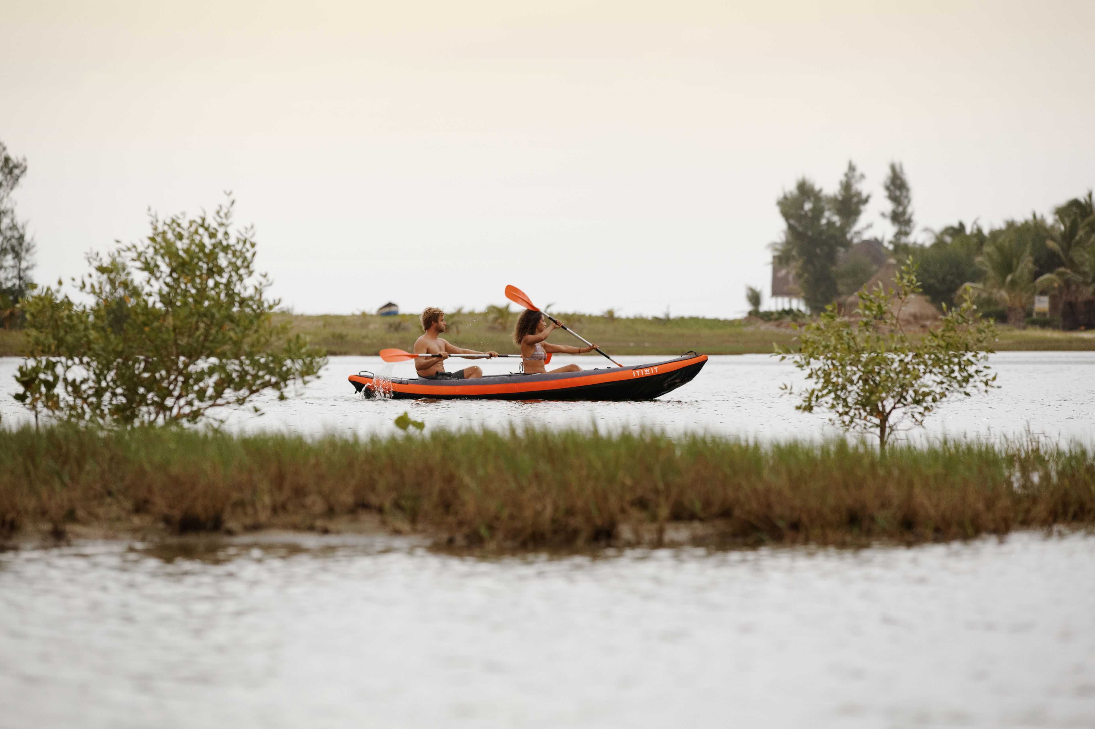 Deux personnes dans un petit bateau sur une étendue d’eau calme, entourée de verdure.