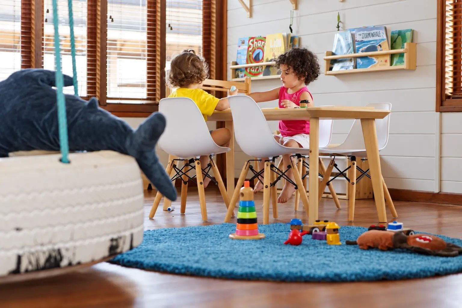 A room with a wooden floor, a blue rug, and a white chair.