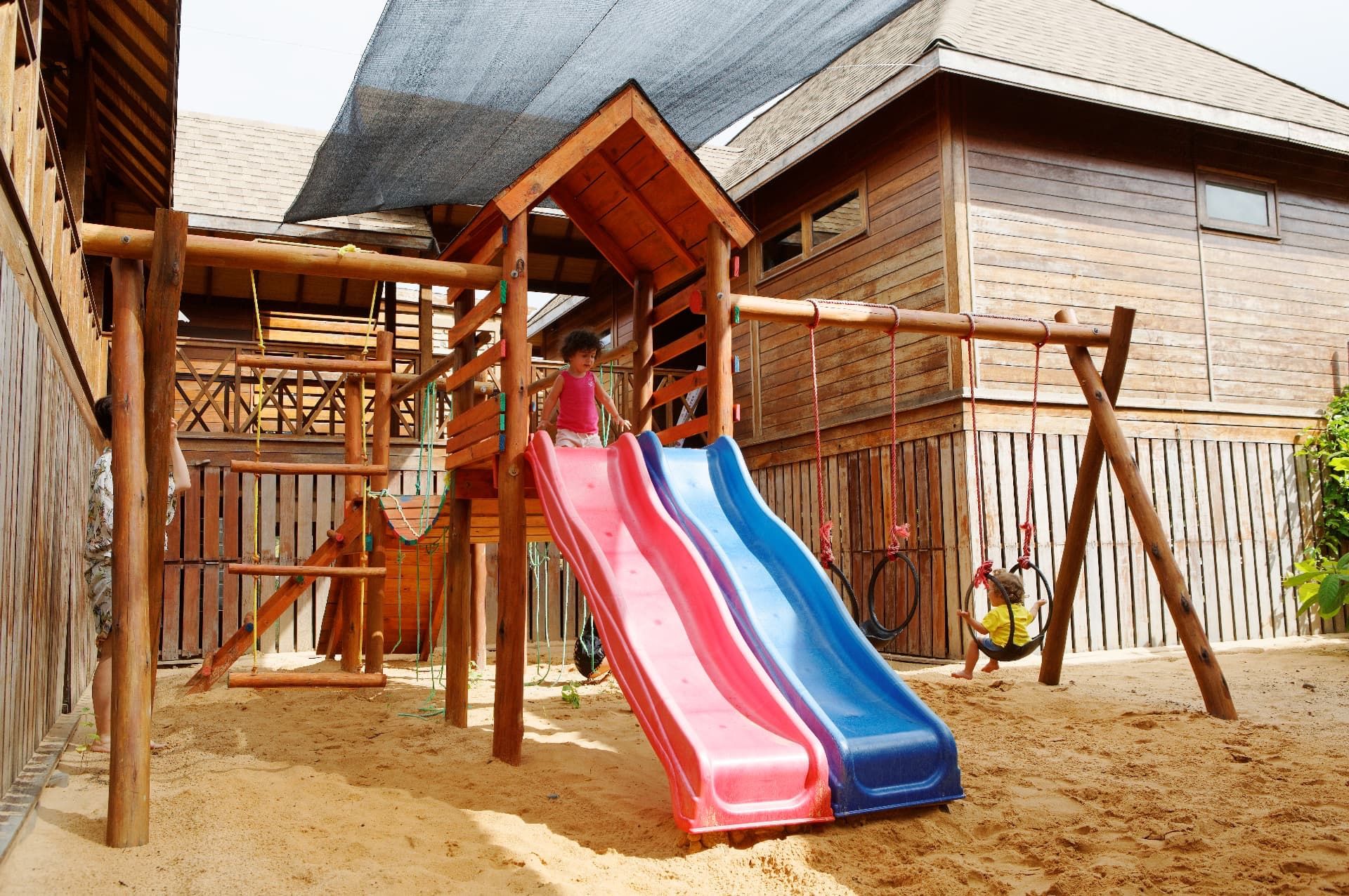 Una estructura de juego de madera con tobogán y elementos para trepar.