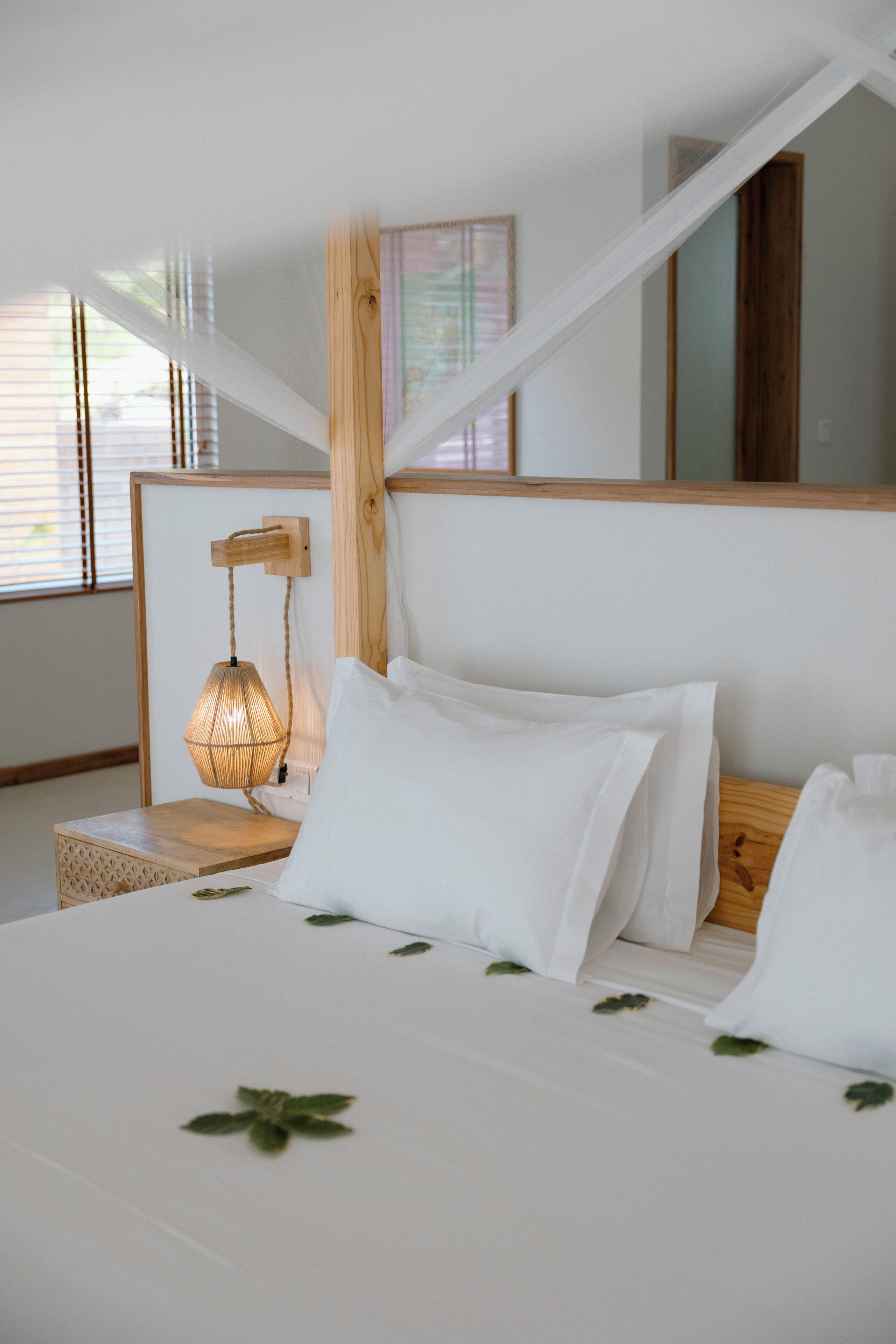 A bedroom with a wooden headboard, a bedside lamp, and a bed with white bedding.
