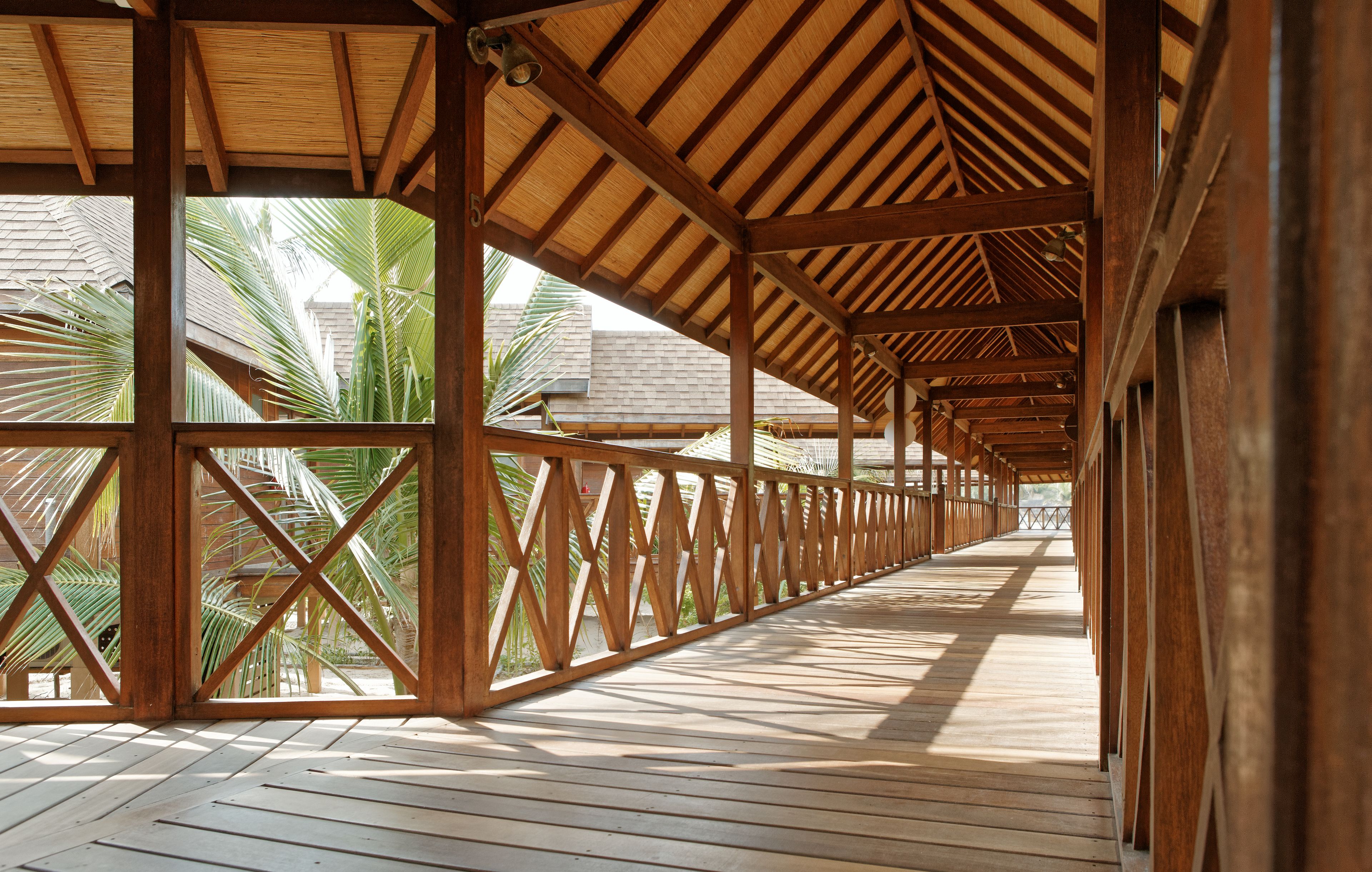 A covered wooden deck with a view of palm trees.