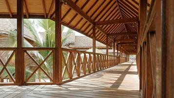 A covered wooden deck with a view of palm trees.