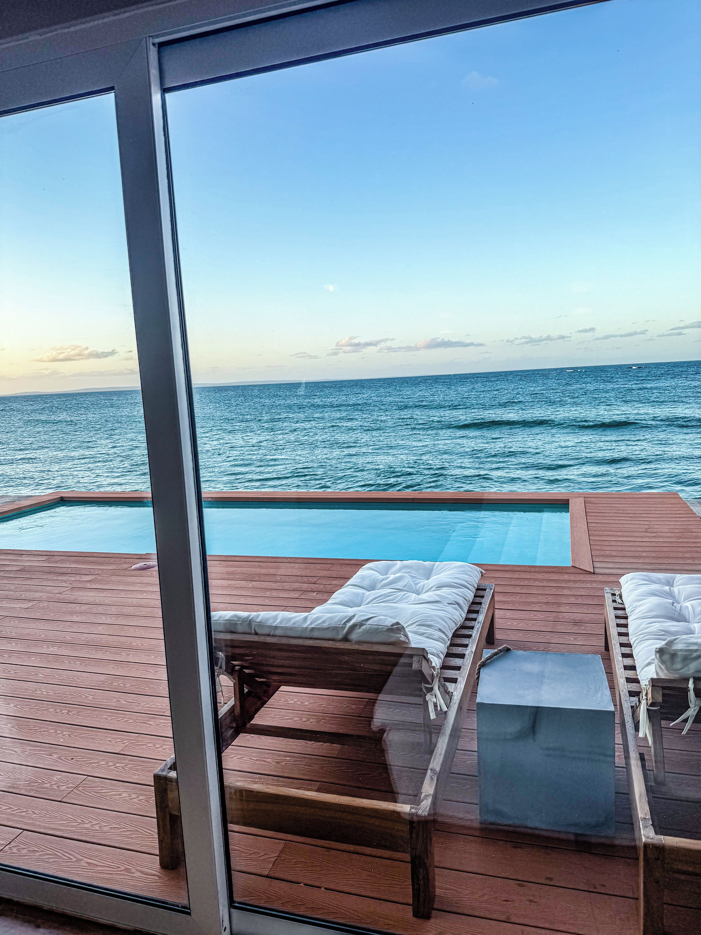 A wooden deck with a pool and lounge chairs.