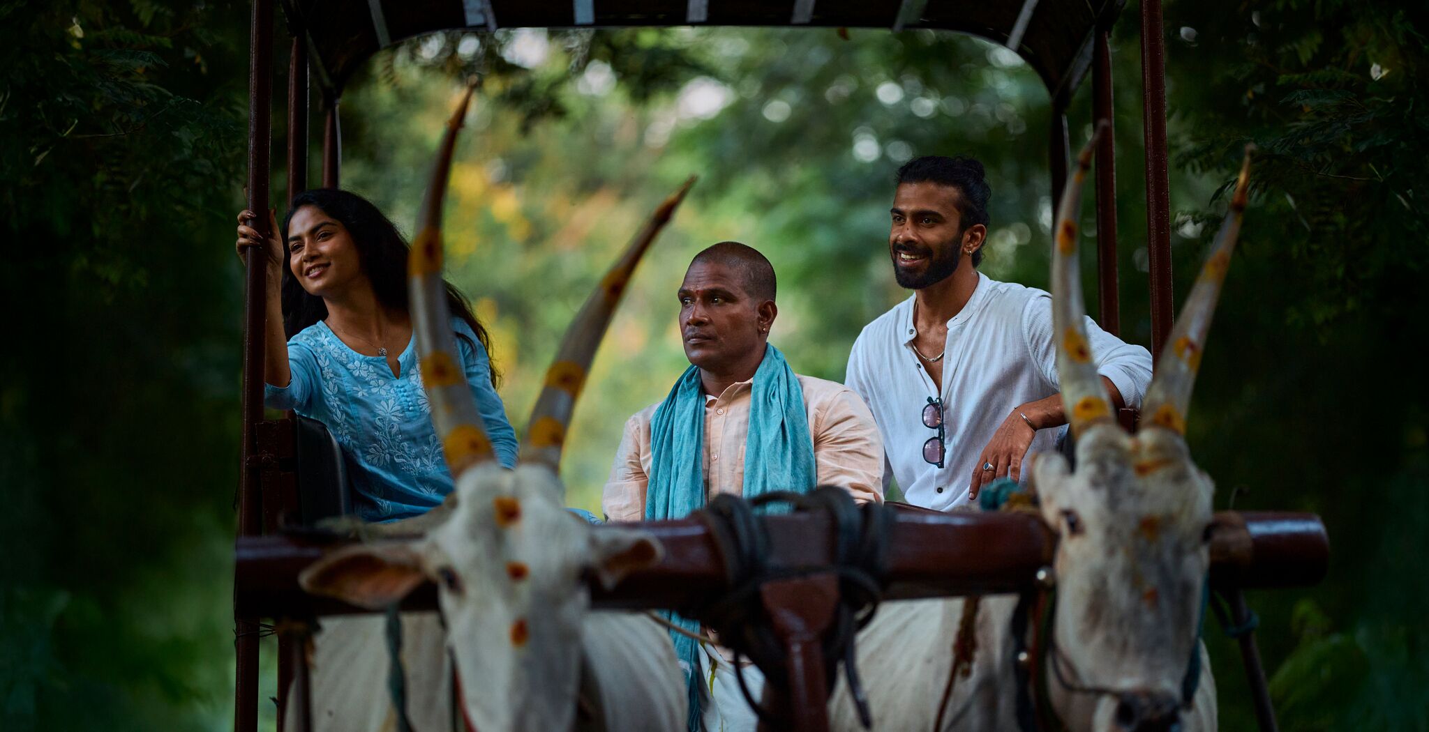 A group of people in a rustic setting with a wooden structure and a natural backdrop.