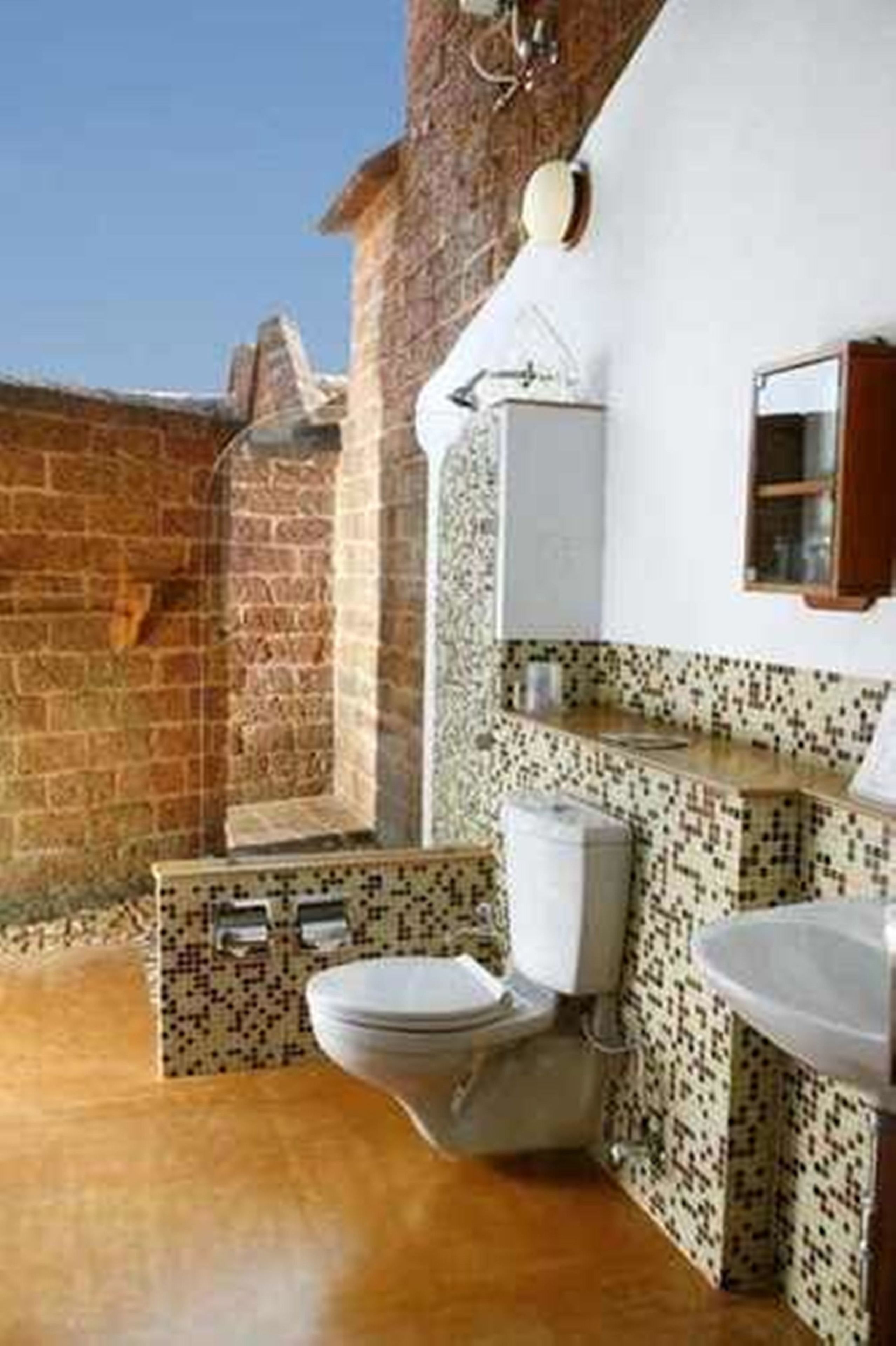 A bathroom with a toilet, sink, and a small window.
