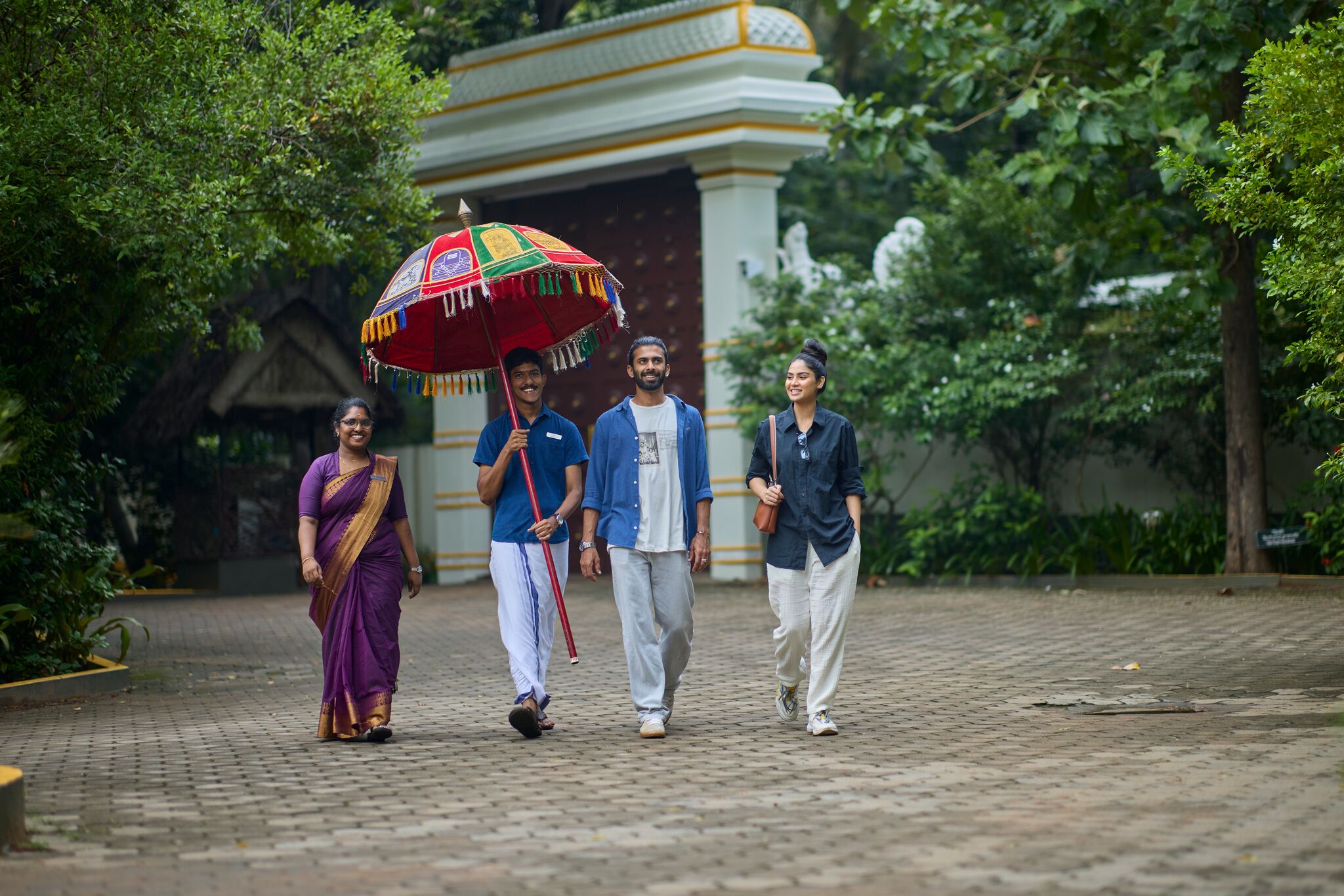 A group of people walking on a paved pathway with a traditional building in the background.