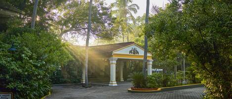 A paved courtyard with a building featuring a central columned structure and a sign indicating a parking area.