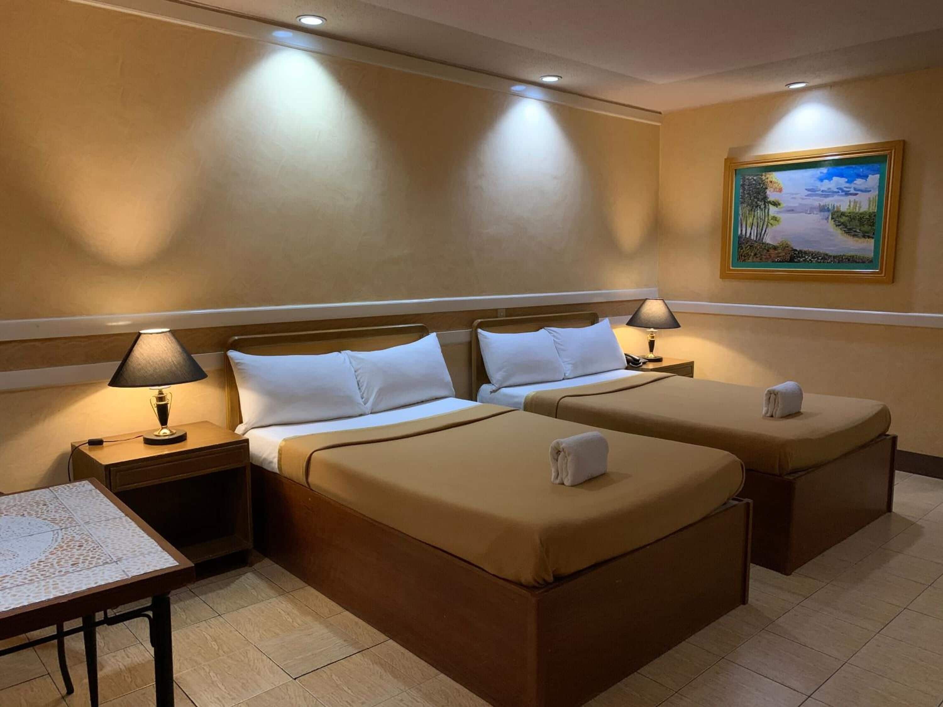 Une chambre d’hôtel avec deux lits, un bureau et un tableau au mur.