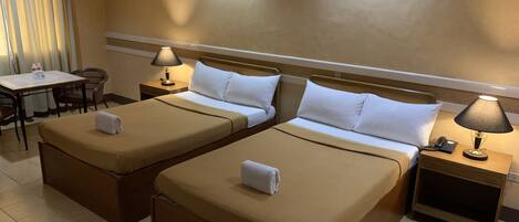 Une chambre d’hôtel avec deux lits, un bureau, des chaises et des lampes.