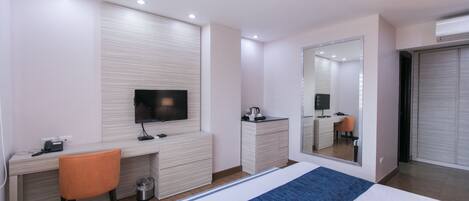 Una habitación de hotel moderna con una cama, un escritorio, una silla, un televisor, un aparador y un armario.