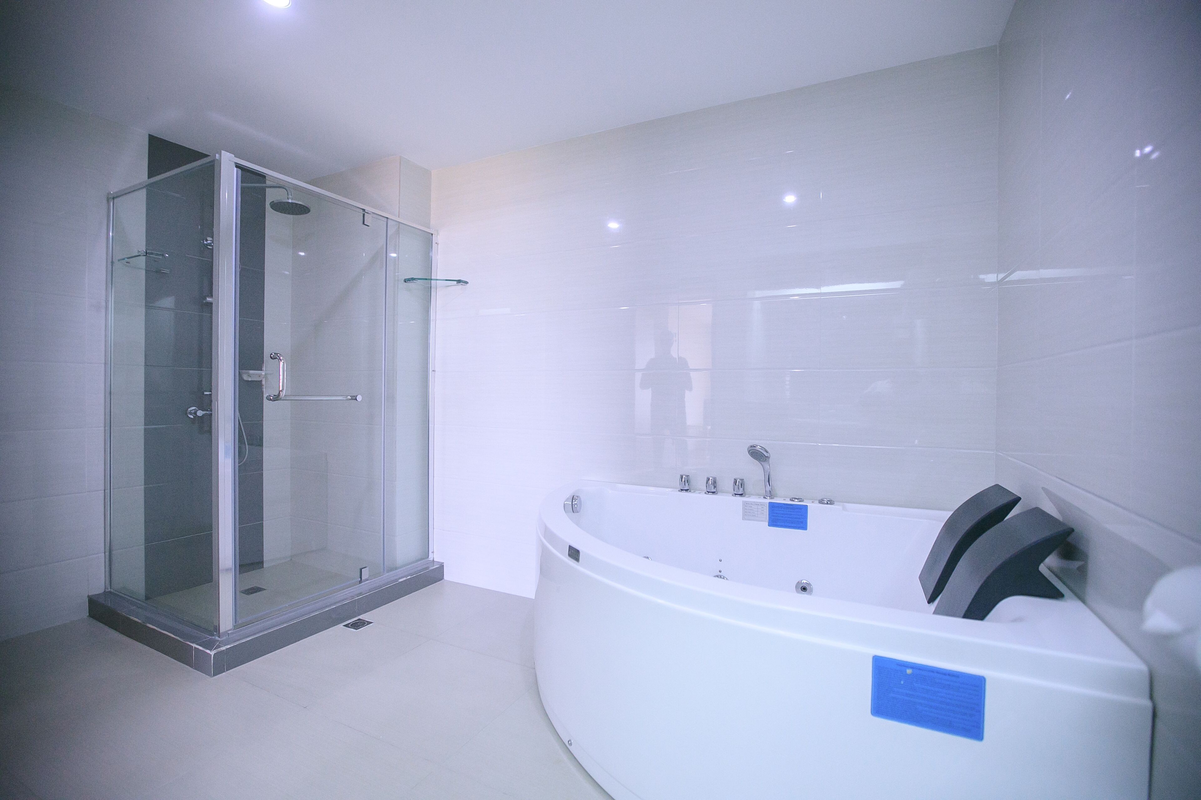 Un baño moderno con ducha de vidrio, una bañera blanca grande y piso de baldosas.