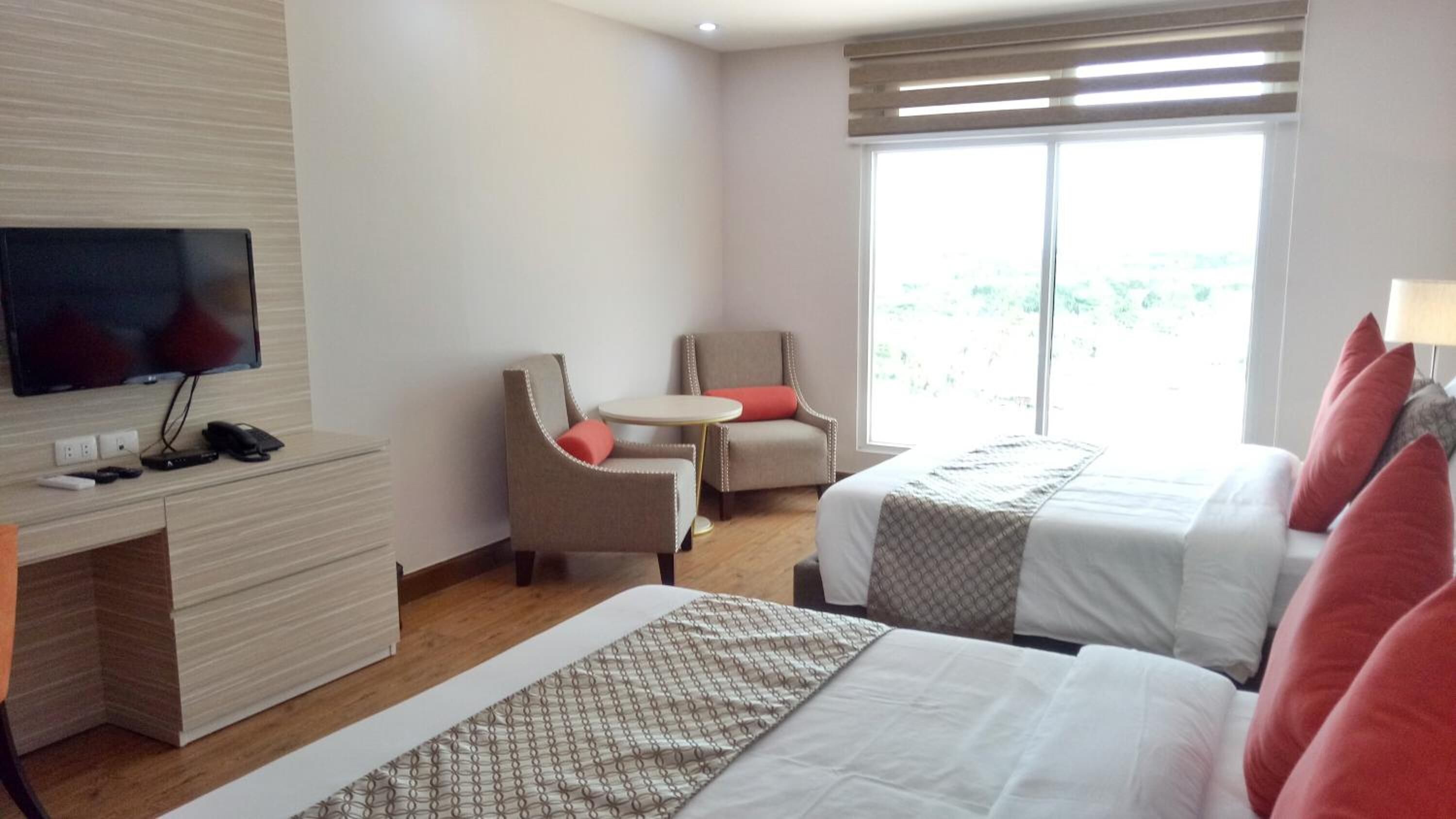 Una habitación de hotel con cama, televisión, escritorio y una silla.