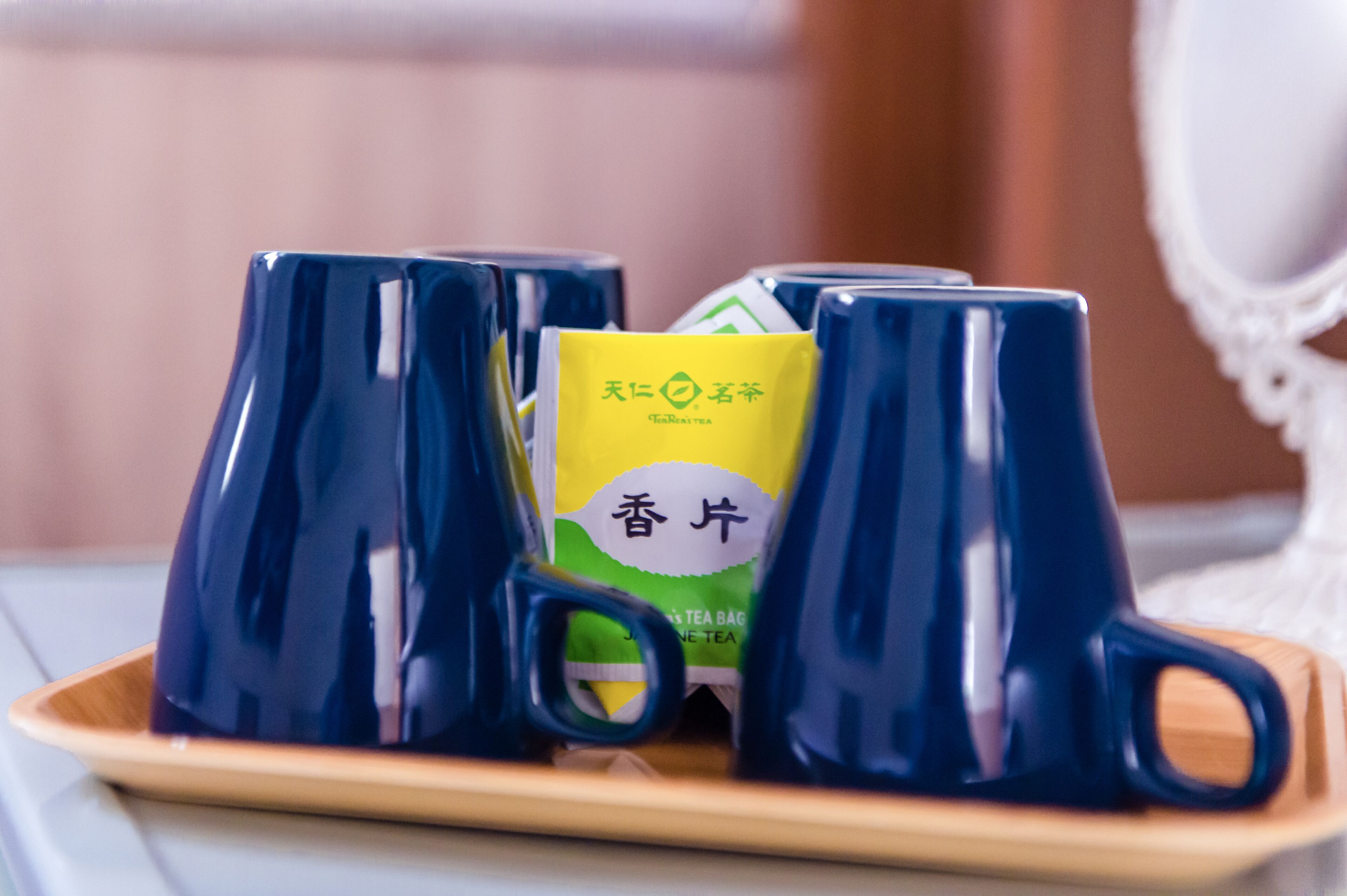 Cuatro tazas azules de cerámica sobre una bandeja con un paquete de té verde y amarillo en el centro.