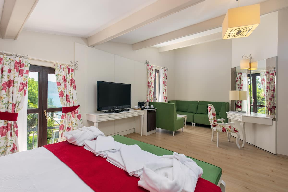 A hotel room with a bed, a desk, a television, a green sofa, and a chair.