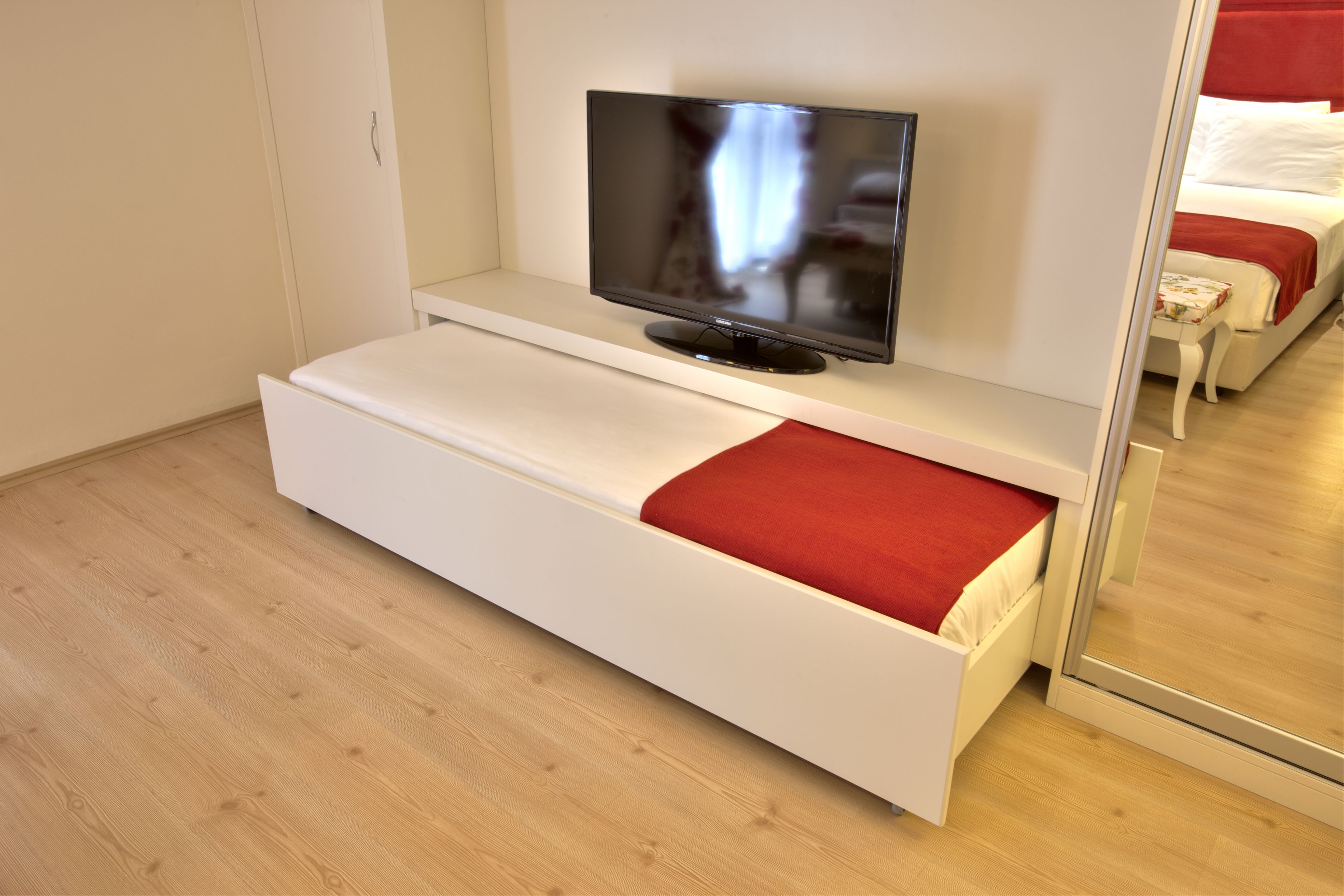 A modern room with a bed, a TV on a stand, and a sliding door.