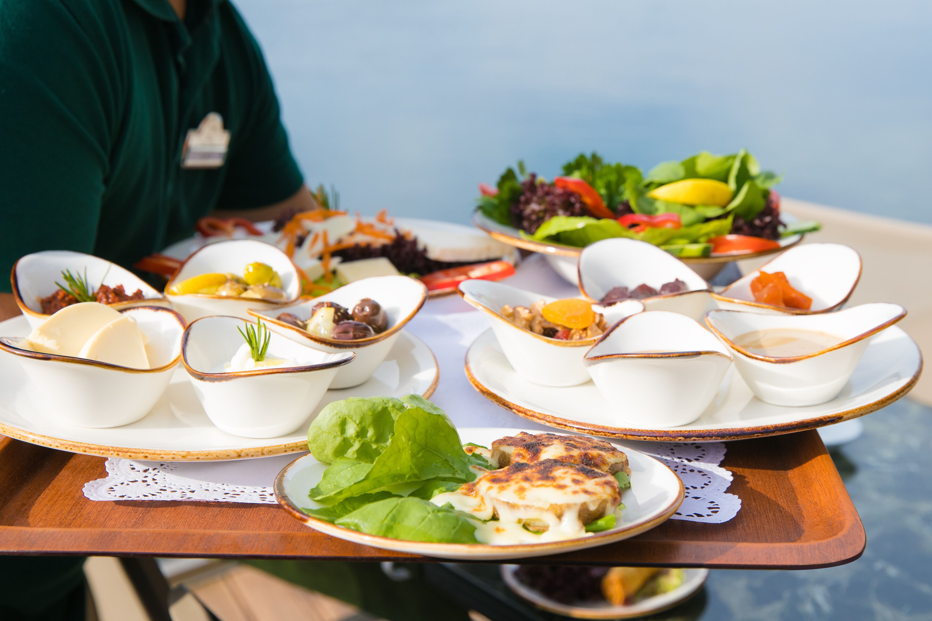 A table with various dishes, including bowls of food and a salad, on a wooden tray.