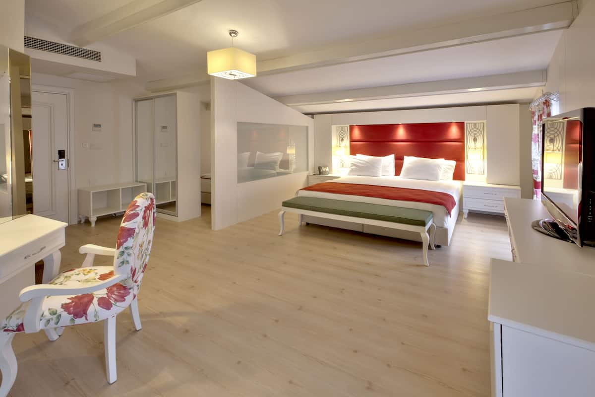 A modern hotel room with a large bed, a desk, and a chair.
